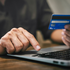 A person at a laptop computer conducts a credit card transaction online.