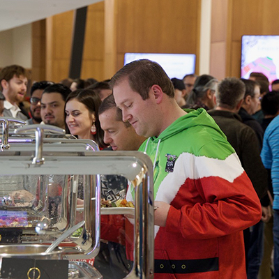 Dax Christensen (green, white, and red hoodie) at the buffet line at the 2024 UIT Holiday Party