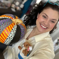 Emily Jacoby, dressed as Bob Ross, holds up the pumpkin she decorated.