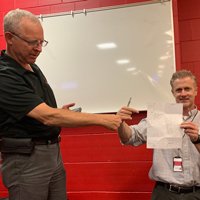 Dan Thornley, left, holds him arm out as Jason Moeller holds up the score sheet showing the winning team.