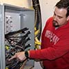 Telecommunication installation tech Christian Johnson points to fiber-optic cables feeding into the building's main distribution frame (MDF).